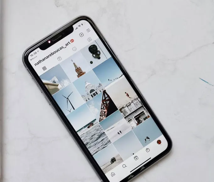smartphone-che-mostra-un-profilo-instagram-creativo-con-griglia-foto-minimal-su-superficie-in-marmo-bianco